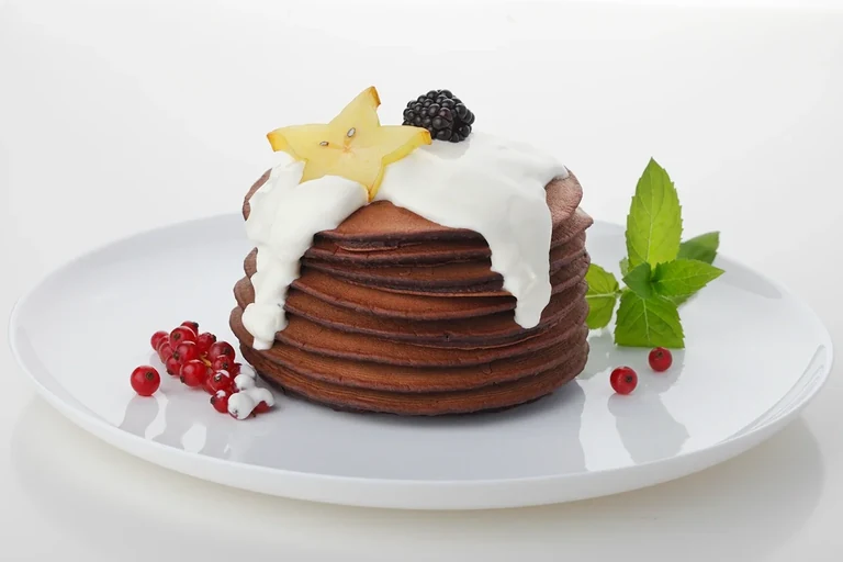 Kulinarmagie — Pfannkuchenstapel mit weißer Sauce und Beeren